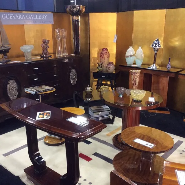 Petite table antique avec un joli design, dans un cadre de galerie, entourée d'autres objets décoratifs.