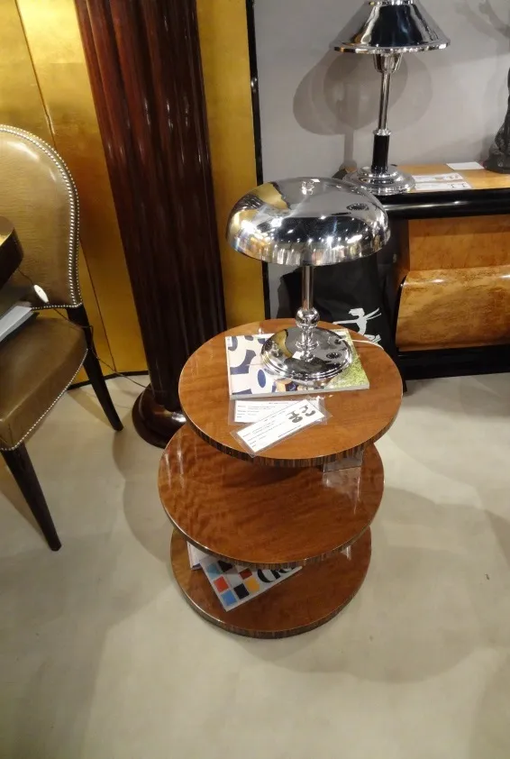 Mesita antigua de tres niveles en un ambiente elegante.