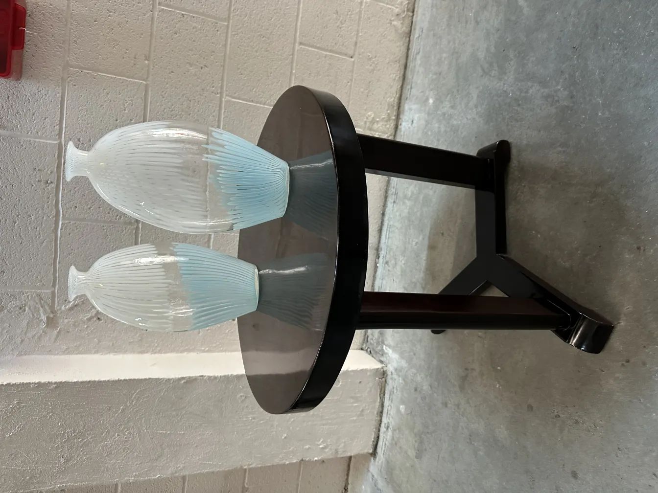 Petite table antique ronde avec deux vases en verre dessus.