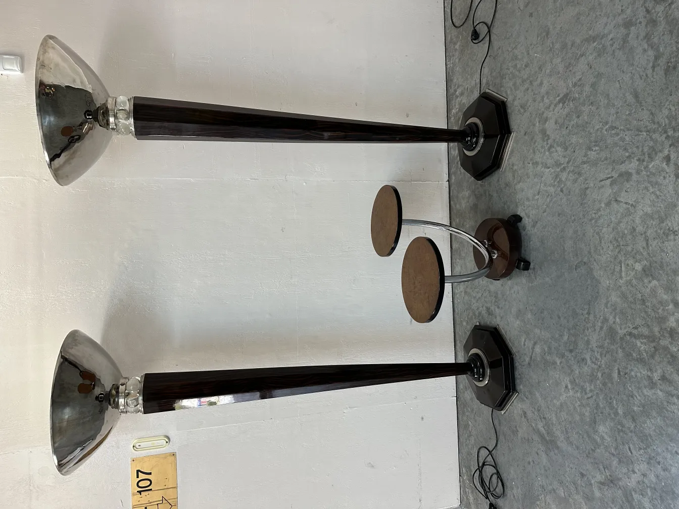 Petite table ancienne à deux niveaux dans un cadre minimaliste, entourée de lampes.