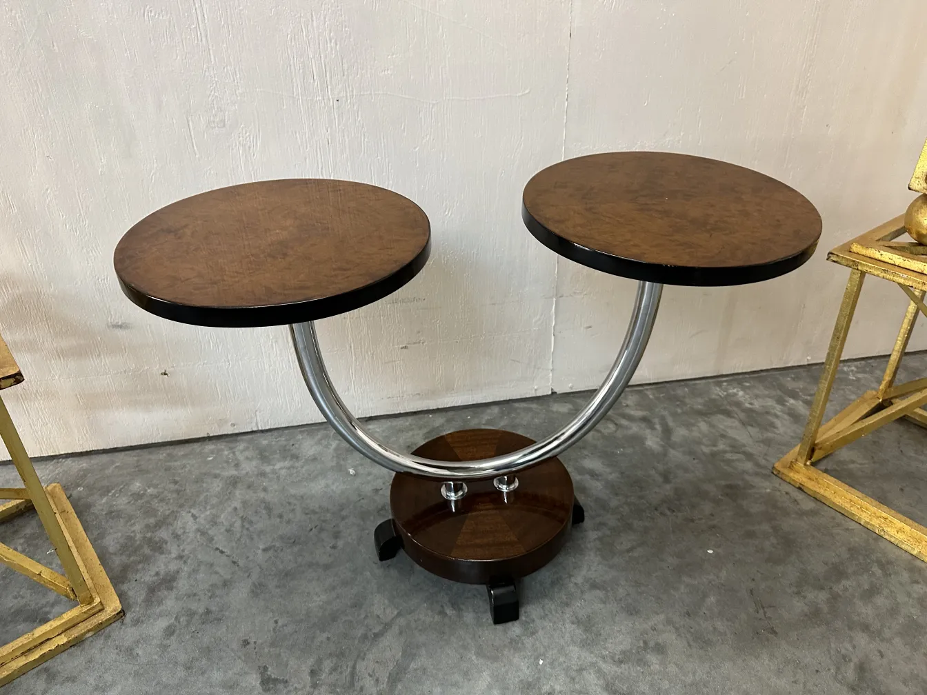 Petite table ancienne avec deux plateaux ronds et une base courbée. Atmosphère d'antiquités.