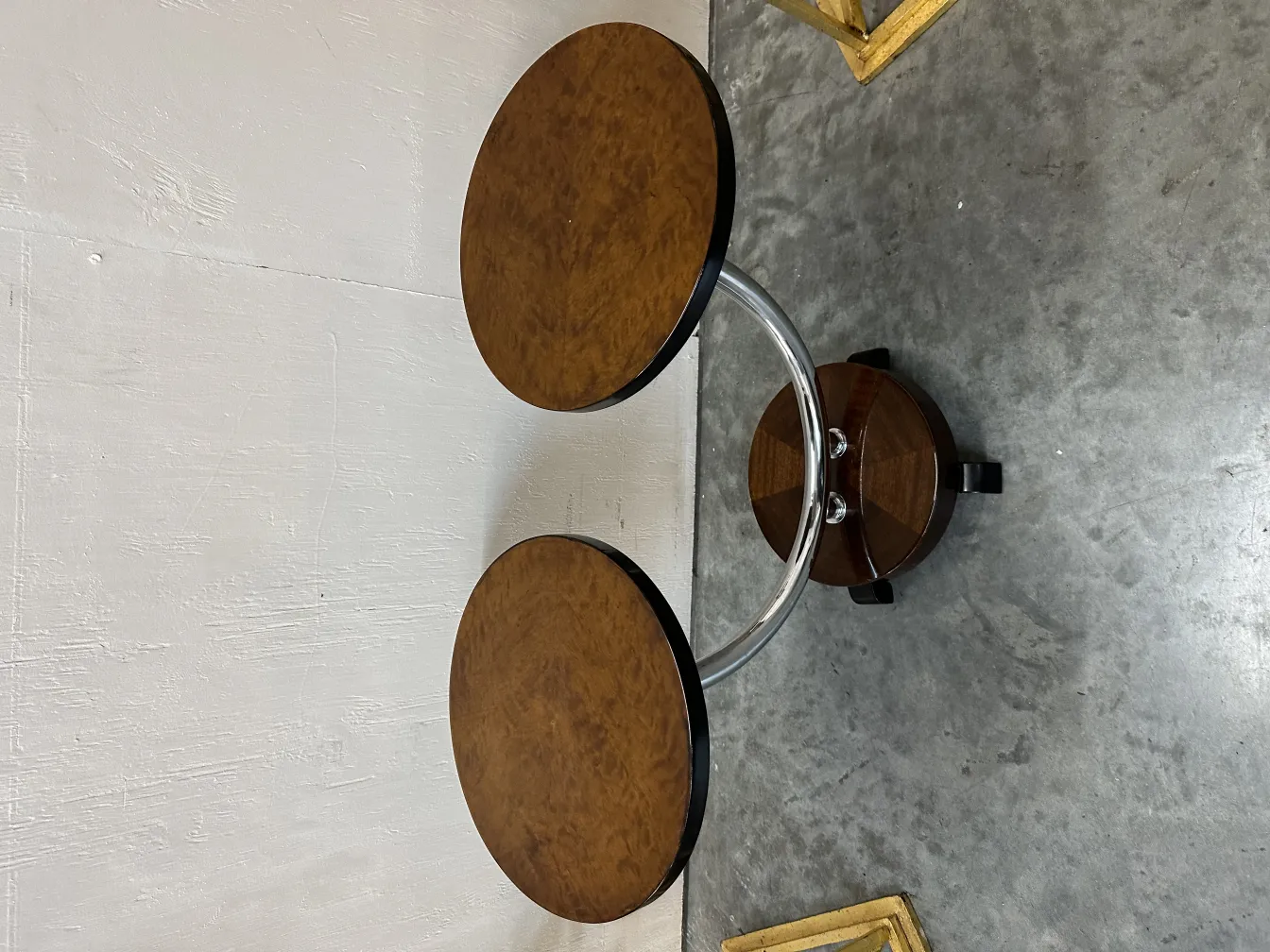 Petite table ancienne avec deux surfaces rondes et une base en métal.
