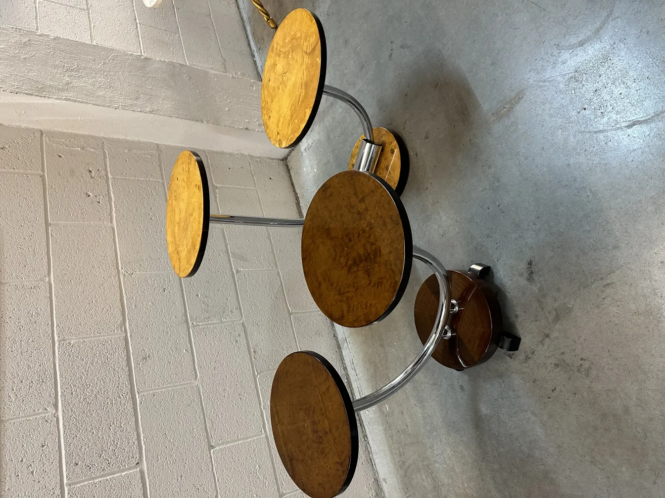 Small antique table with round base and multiple movable legs, in a neutral setting