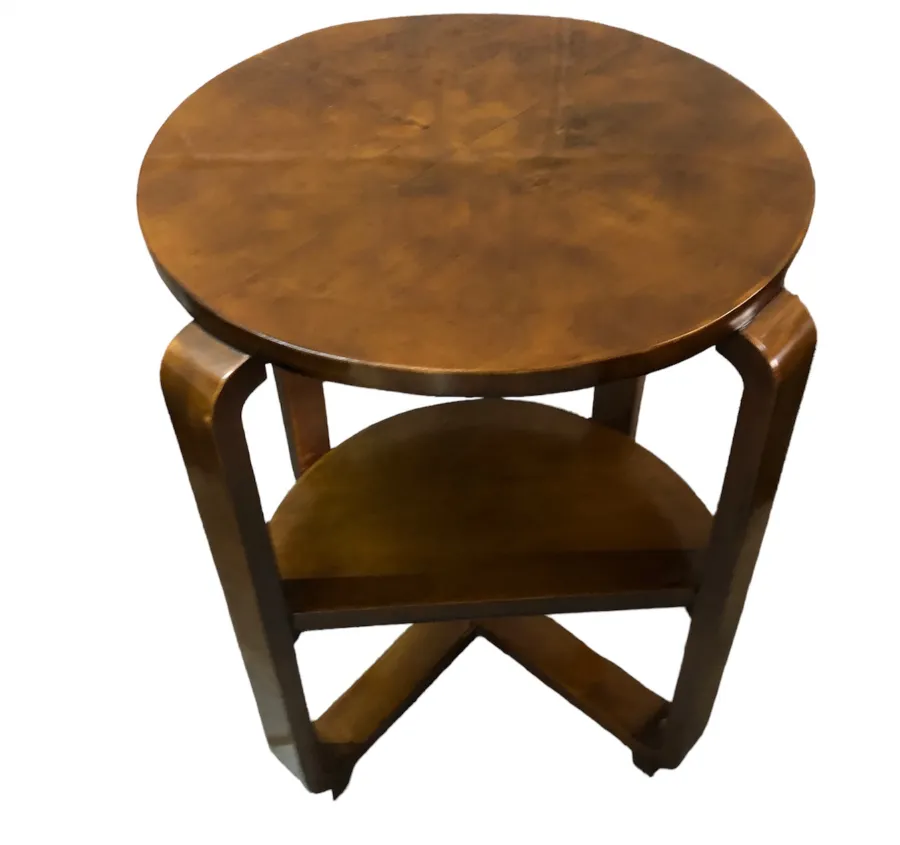 Petite table ronde ancienne avec un étagère en dessous.
