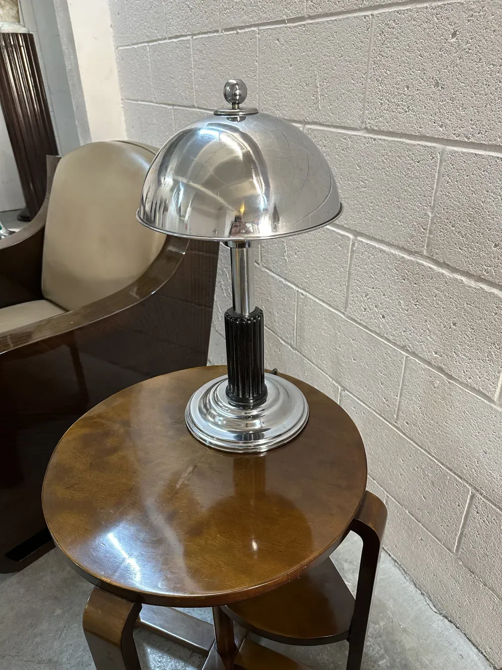 Petite table ronde ancienne avec un design élégant et une lampe au-dessus.