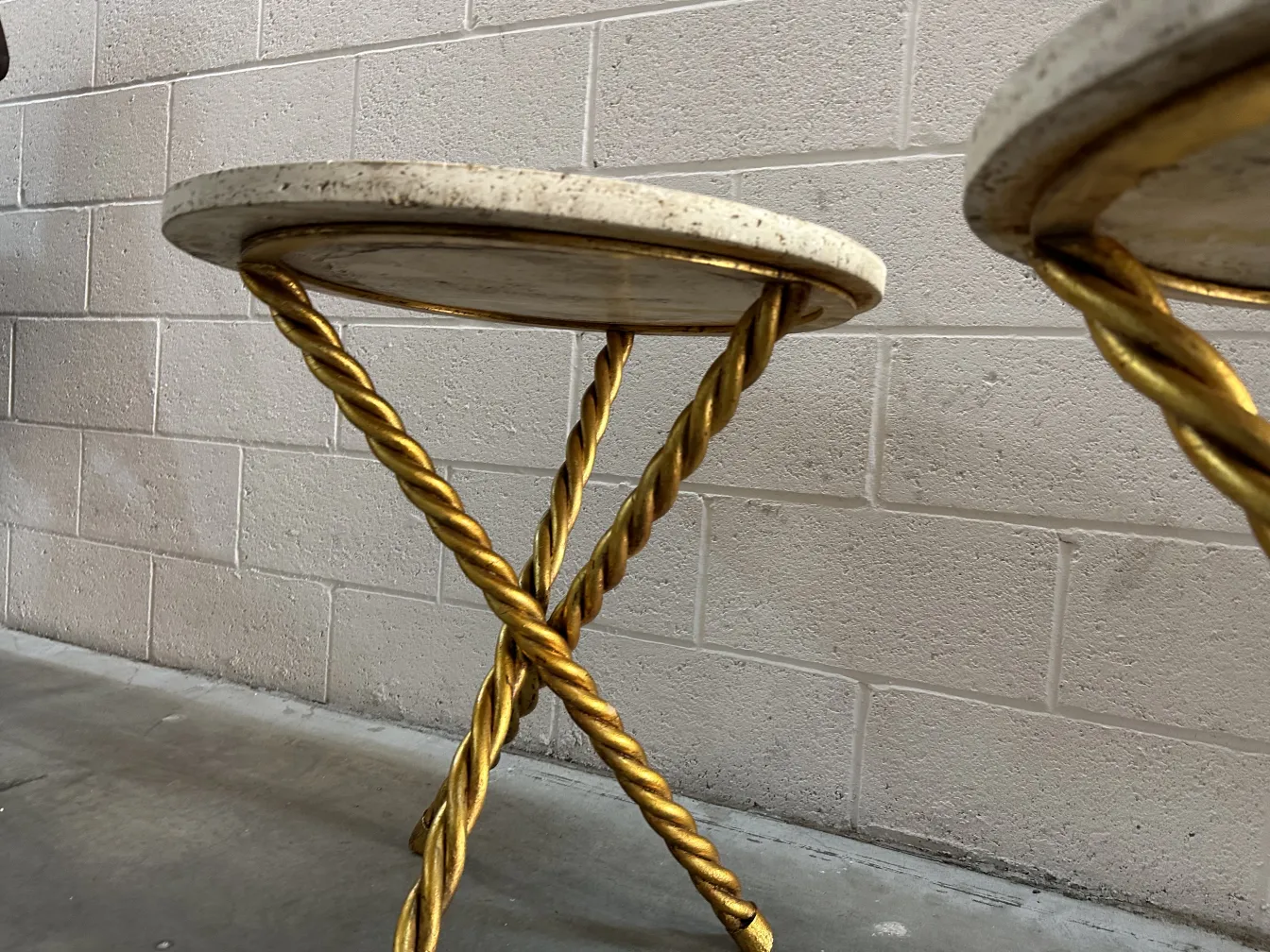 Deux petites tables anciennes avec une base dorée et un plateau clair dans un cadre moderne