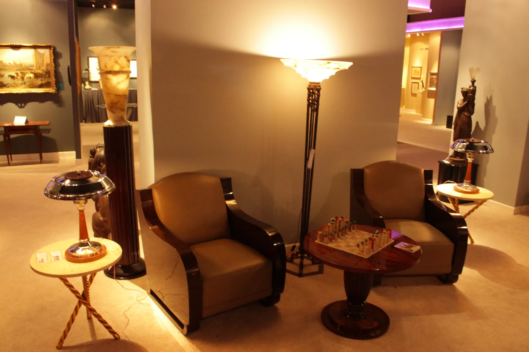 Deux petites tables anciennes à côté de fauteuils dans une salle élégante avec une lampe