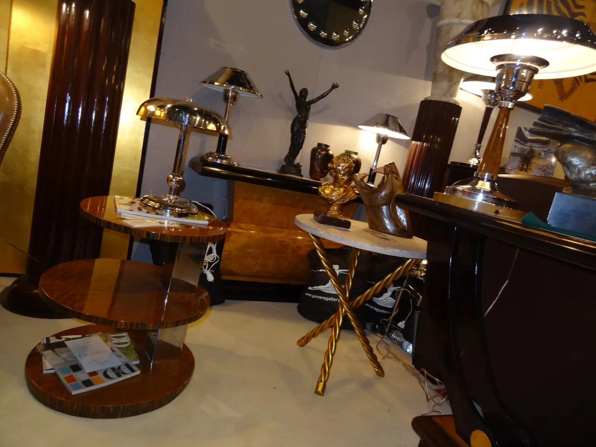 Two antique small tables in a decorative setting with lamps and sculptures