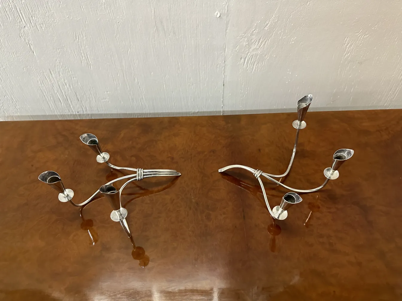 Conjunto de 2 castiçais antigos, com formas elegantes e detalhes decorativos, sobre uma superfície polida.