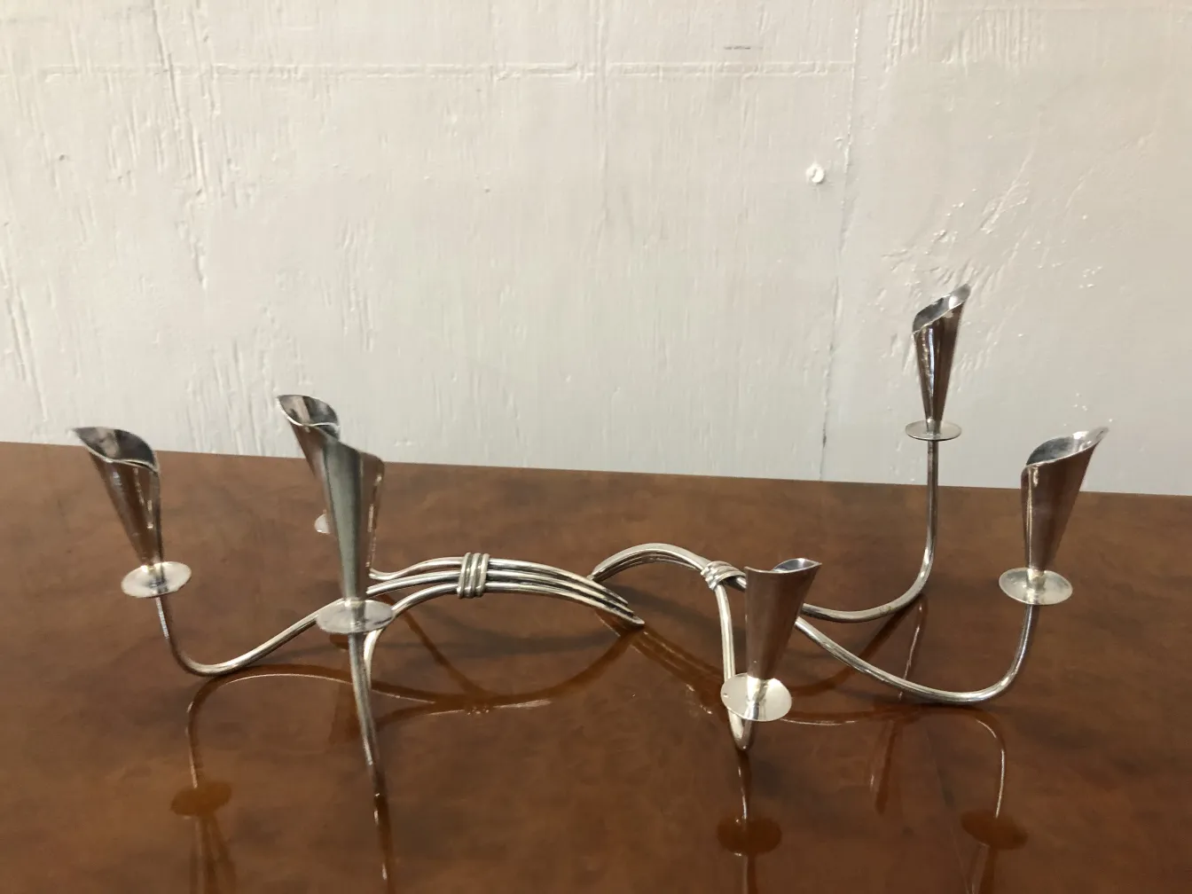 Due candelabri antichi con dettagli decorativi, forme eleganti e finitura lucida su sfondo neutro