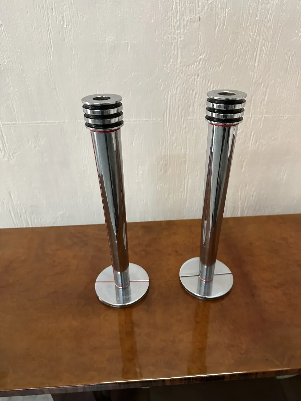 2 candélabres anciens en métal sur une table en bois, doucement éclairés.