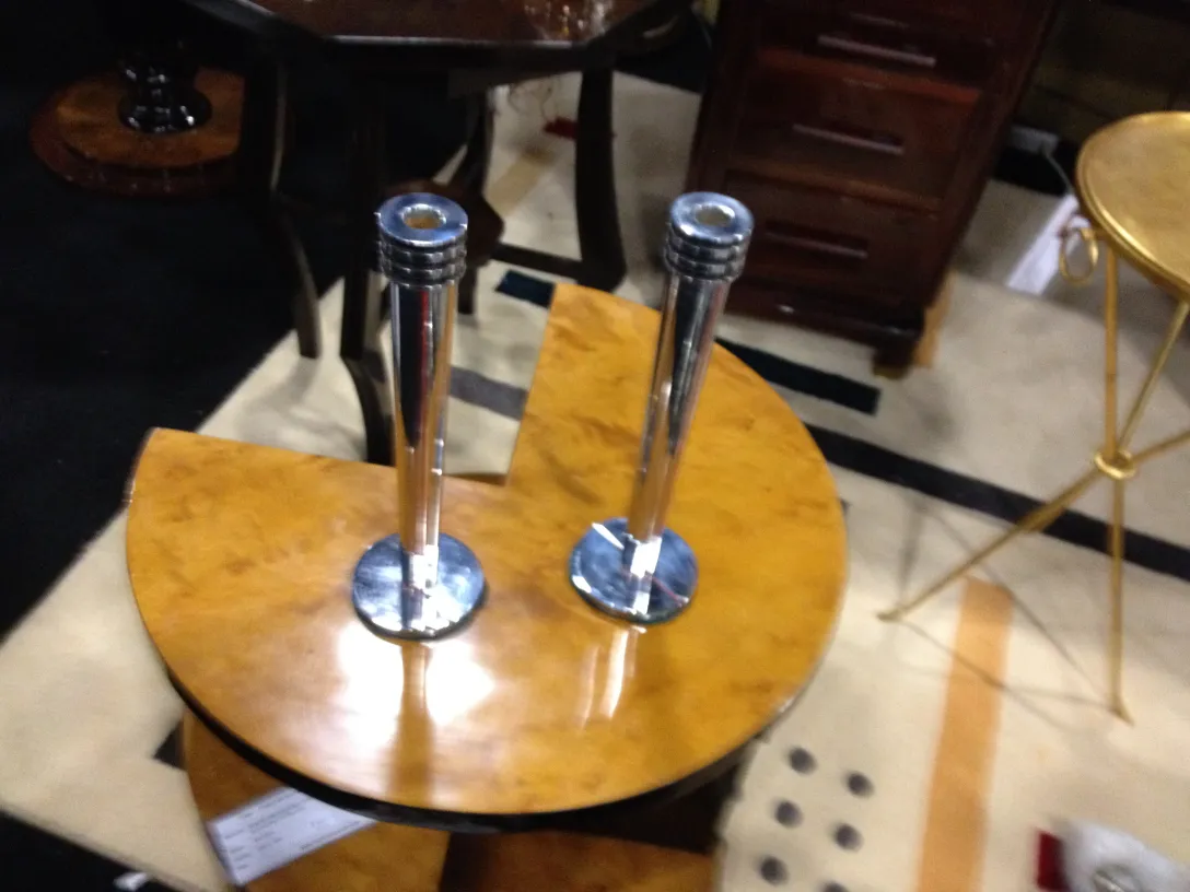 Dois castiçais antigos em uma mesa, fundo variado.