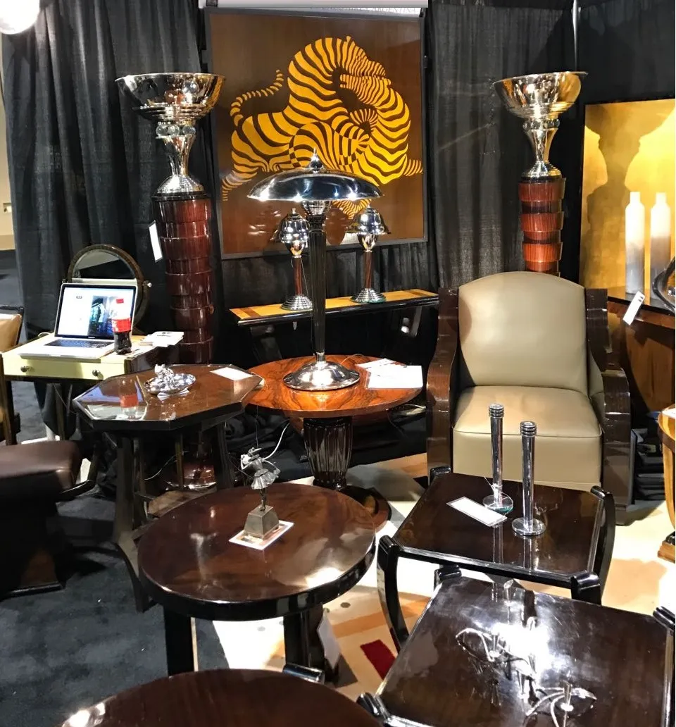 2 antique candelabras displayed with tables and chairs in a dark setting.