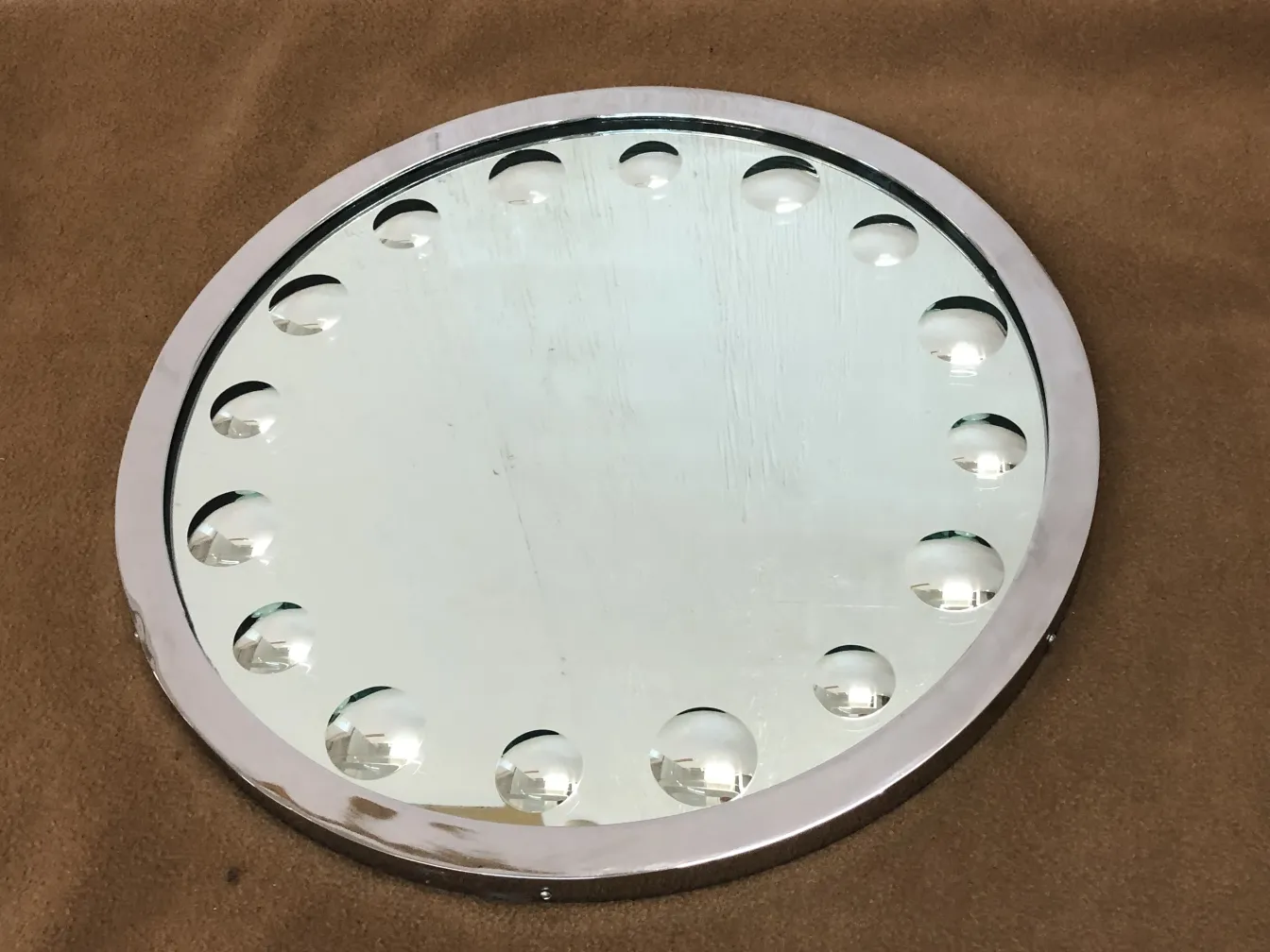 runder antiker Spiegel mit Reliefdetails, brauner Hintergrund