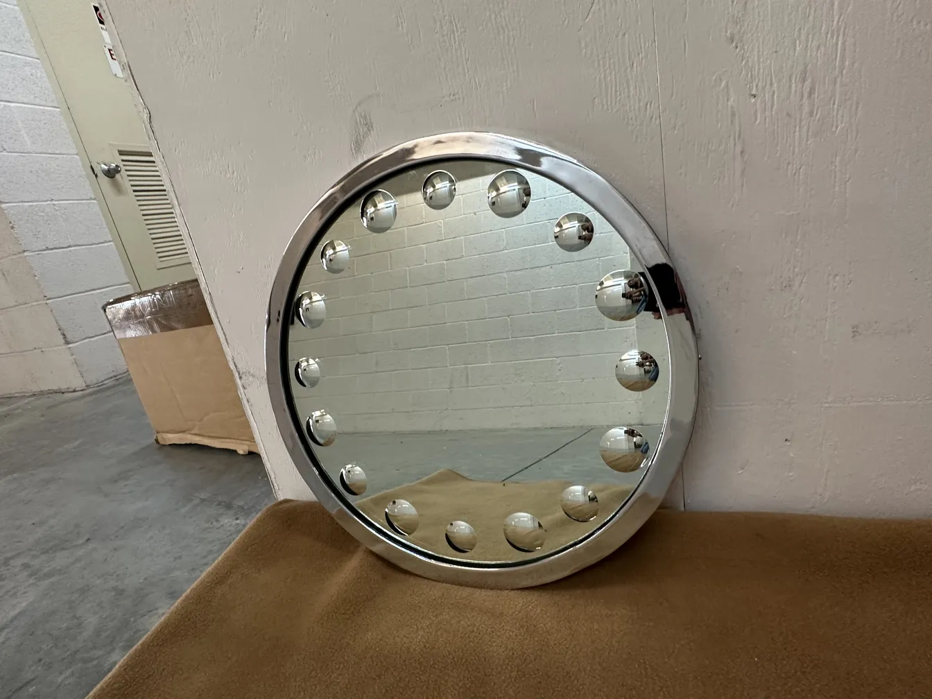 Miroir antique rond avec décoration circulaire et lumières. Fond neutre.