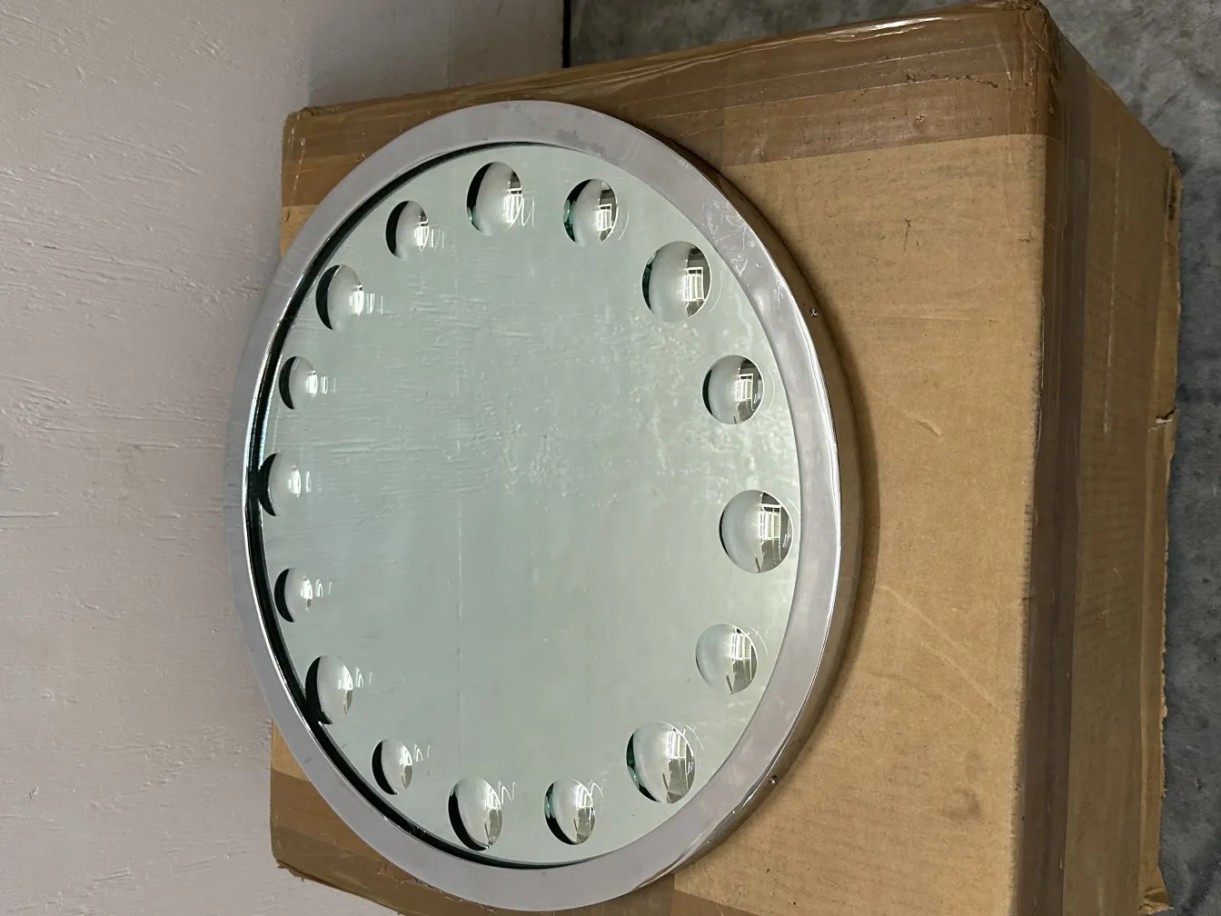 Espelho antigo com uma moldura decorativa e detalhes sutis. Visto em um ambiente neutro.