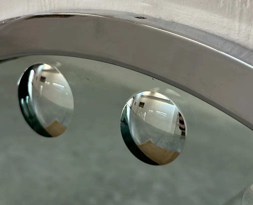 Two antique round mirrors on a white wall creating subtle reflections.