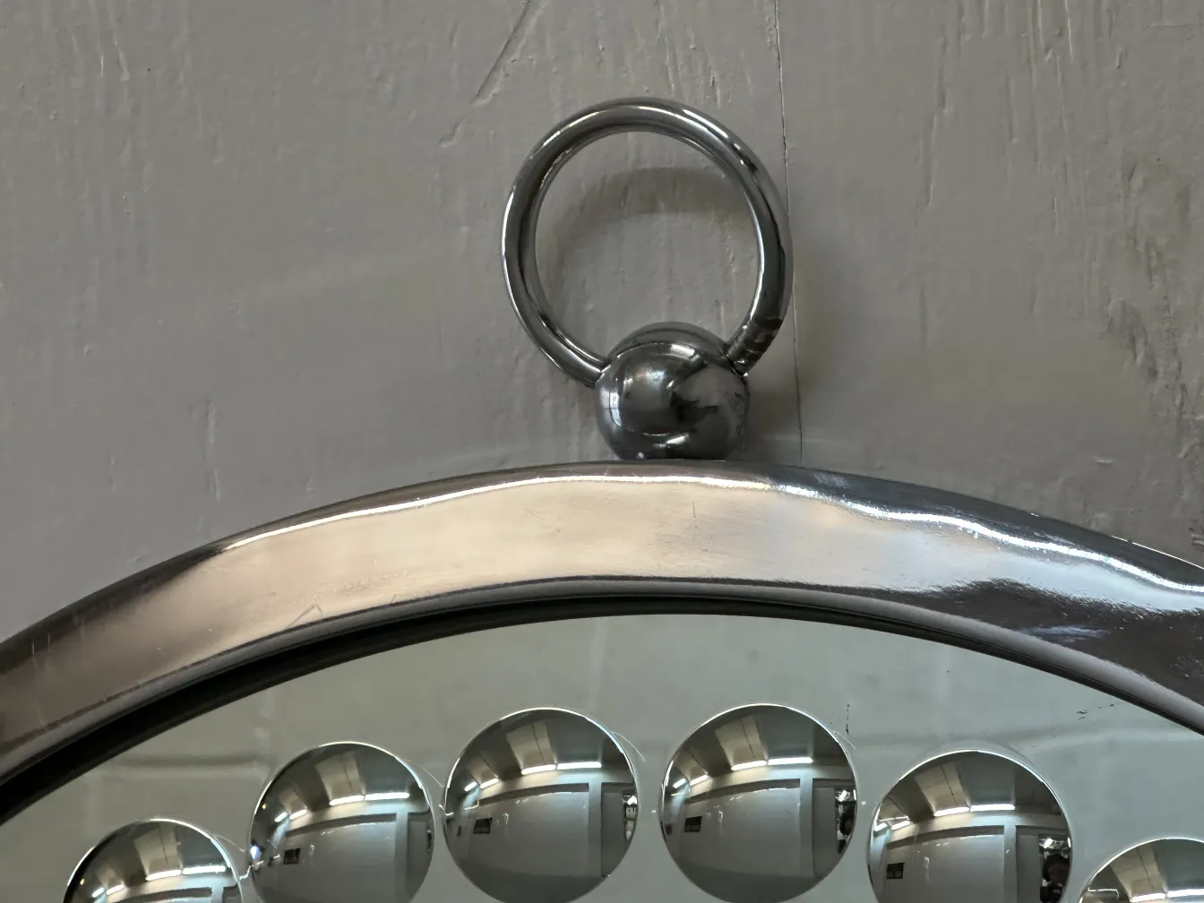 Deux miroirs anciens décoratifs, avec un cadre incurvé et des détails arrondis, dans un environnement neutre.