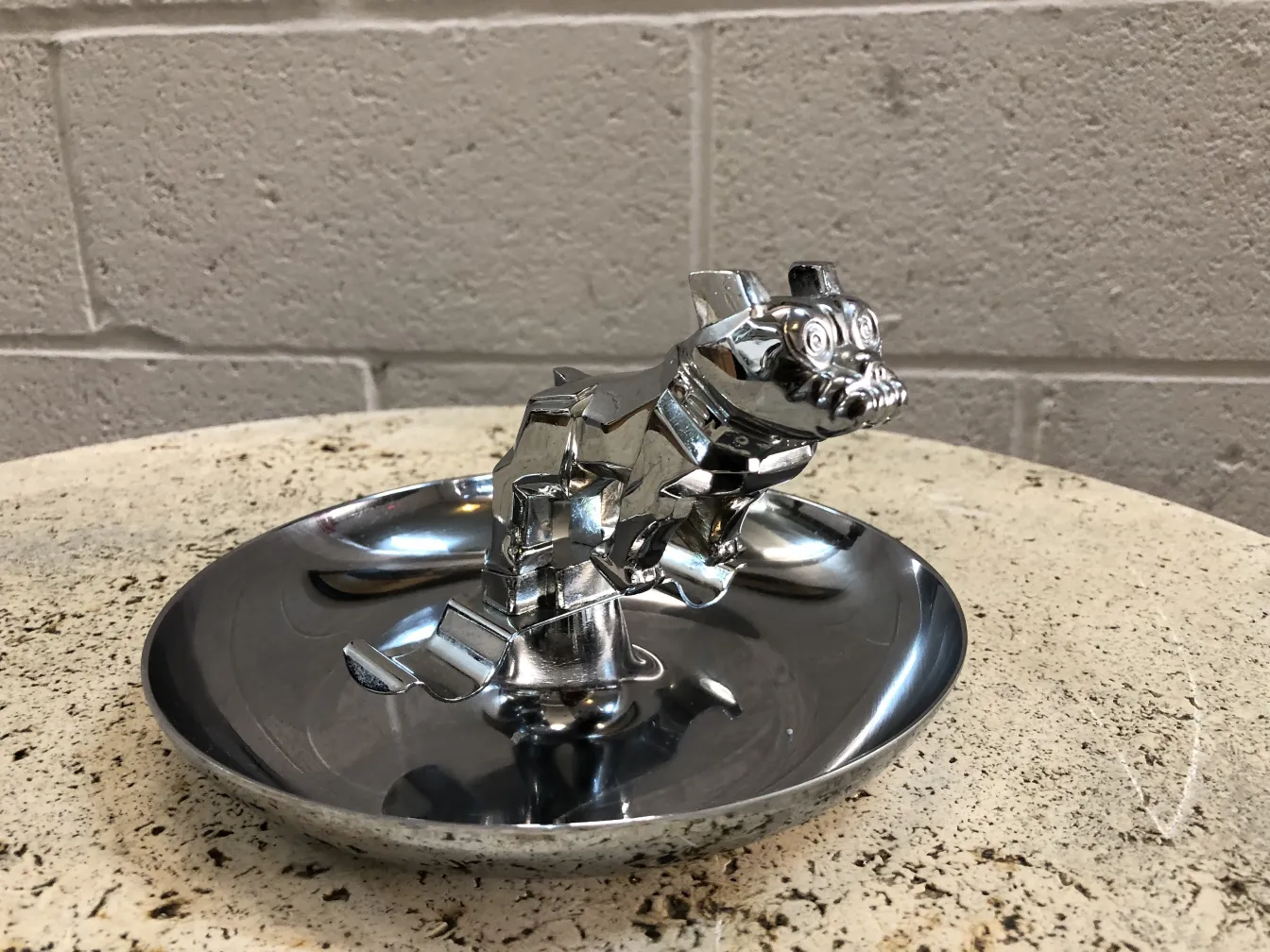 Antique ashtray shaped like a dog with a shiny surface.