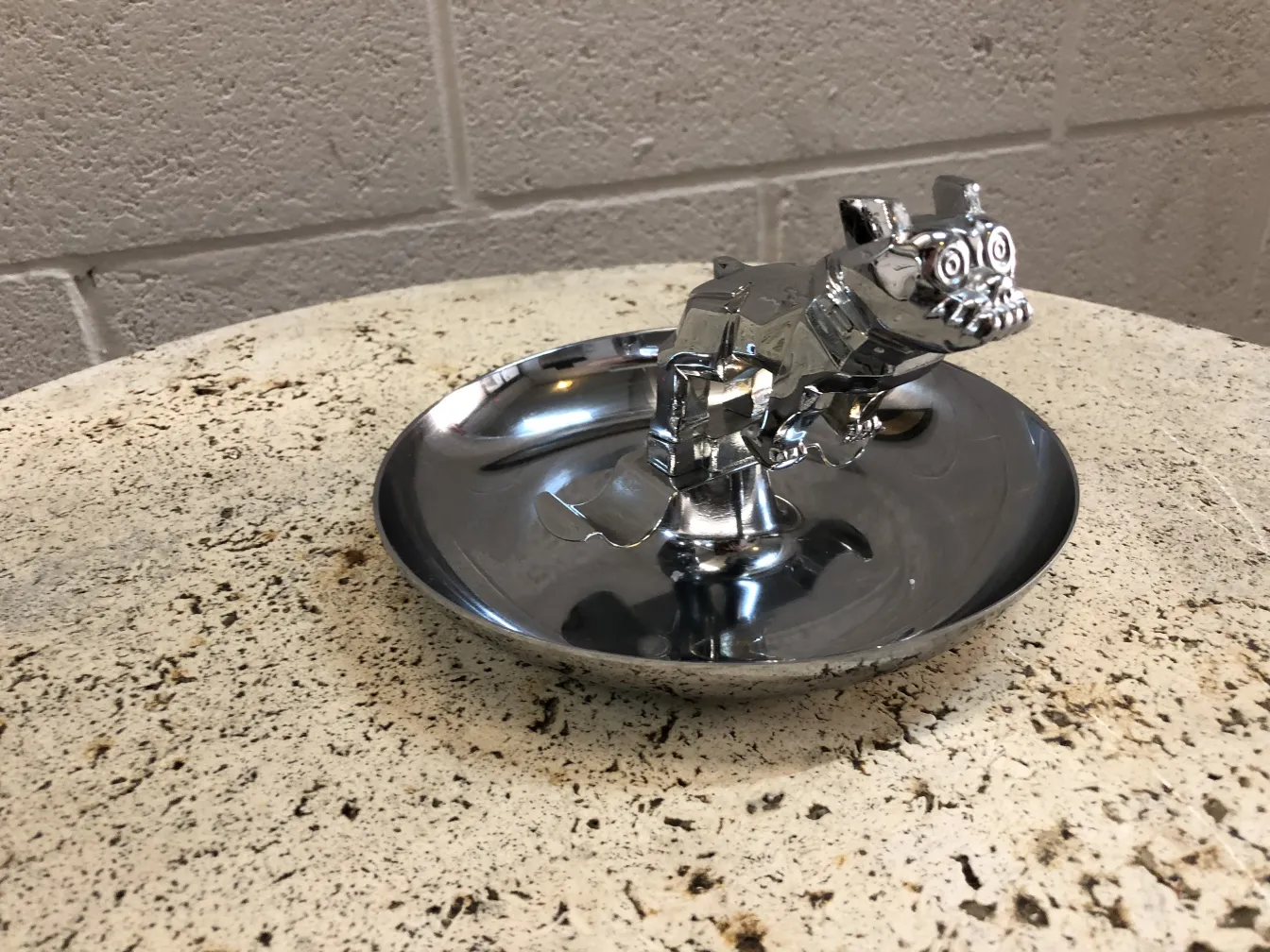 Cenicero antiguo con forma de perro, brilla en una mesa