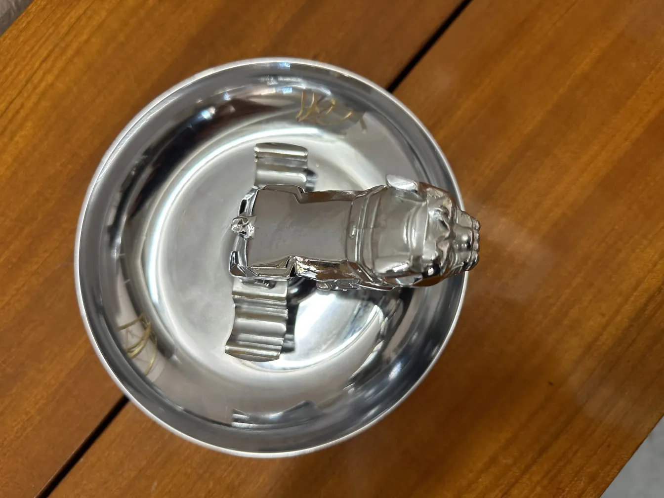 Antique ashtray featuring a decorative figure on top and a shiny base.