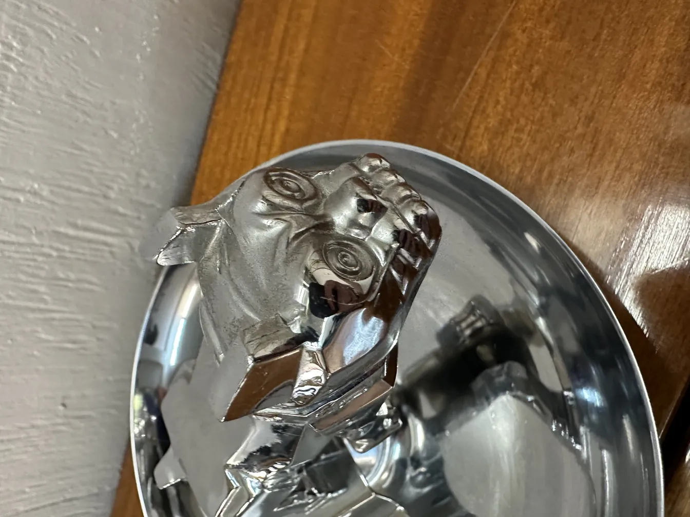 Cenicero antiguo con diseño elegante en forma de figura sobre una mesa de madera.