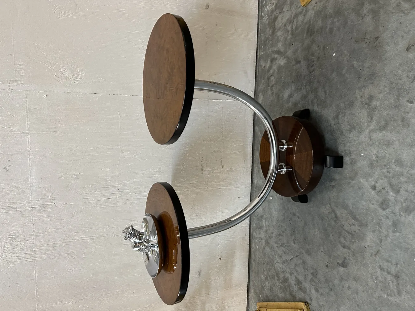 Cinzeiro antigo com uma figura decorativa na base, ambiente neutro.