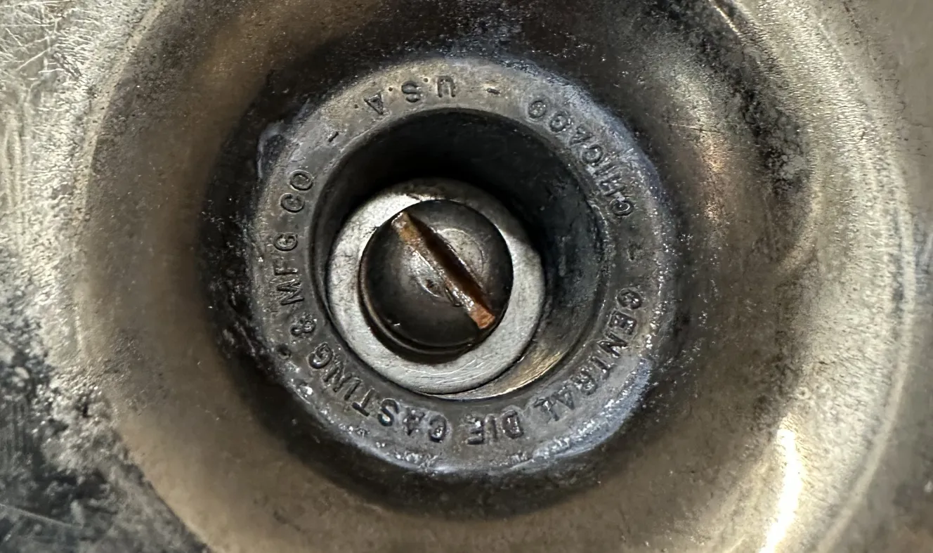 Cendrier ancien rond avec surface texturée, détail de la vis visible au centre.