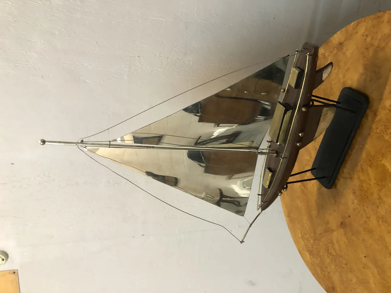 Modelo antigo de barco do designer em escala com velas brilhantes e detalhes elegantes em fundo neutro.