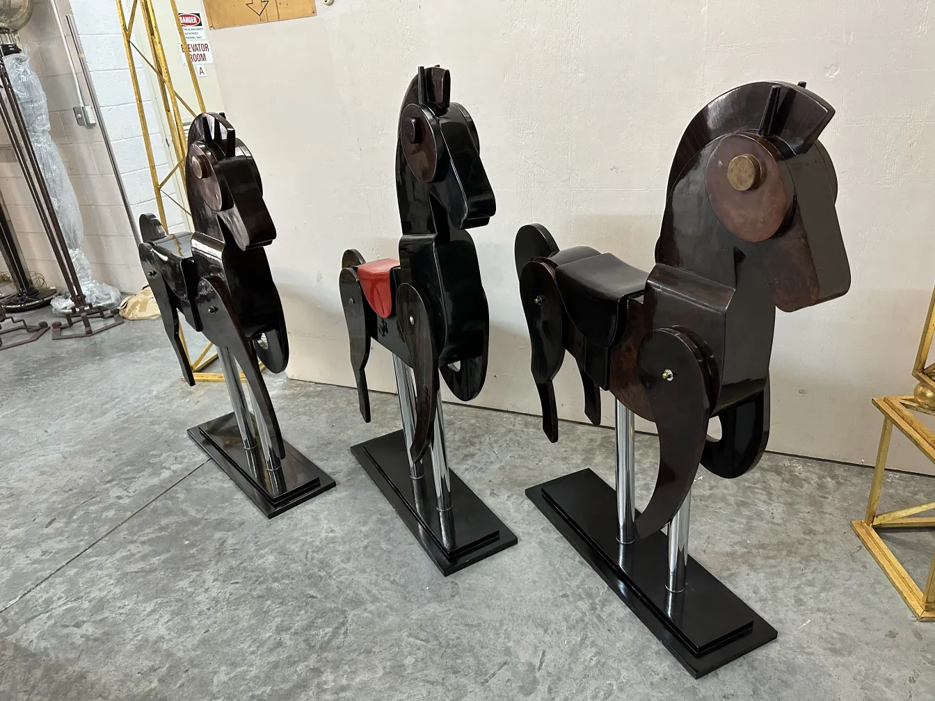 Trois chevaux anciens décoratifs exposés en rangée.