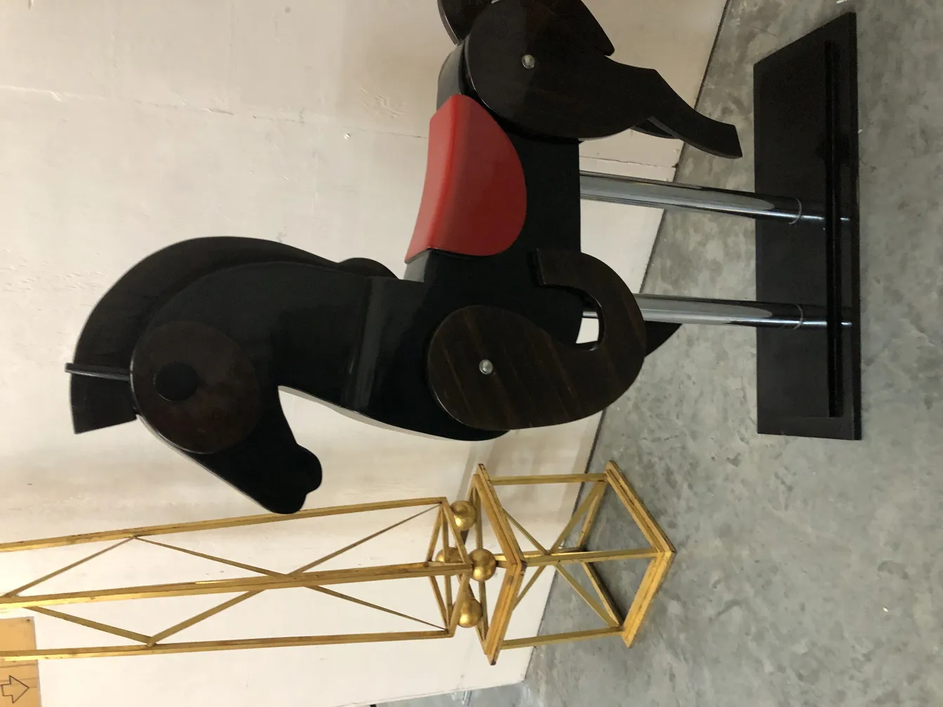 Caballo antiguo de juguete de color negro con silla roja.