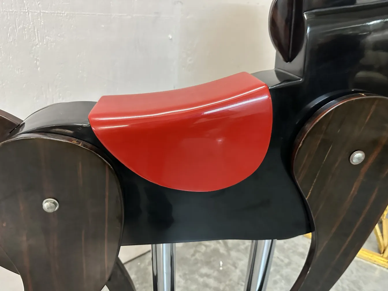 Caballo antiguo en color negro con una silla roja, juguete decorativo.