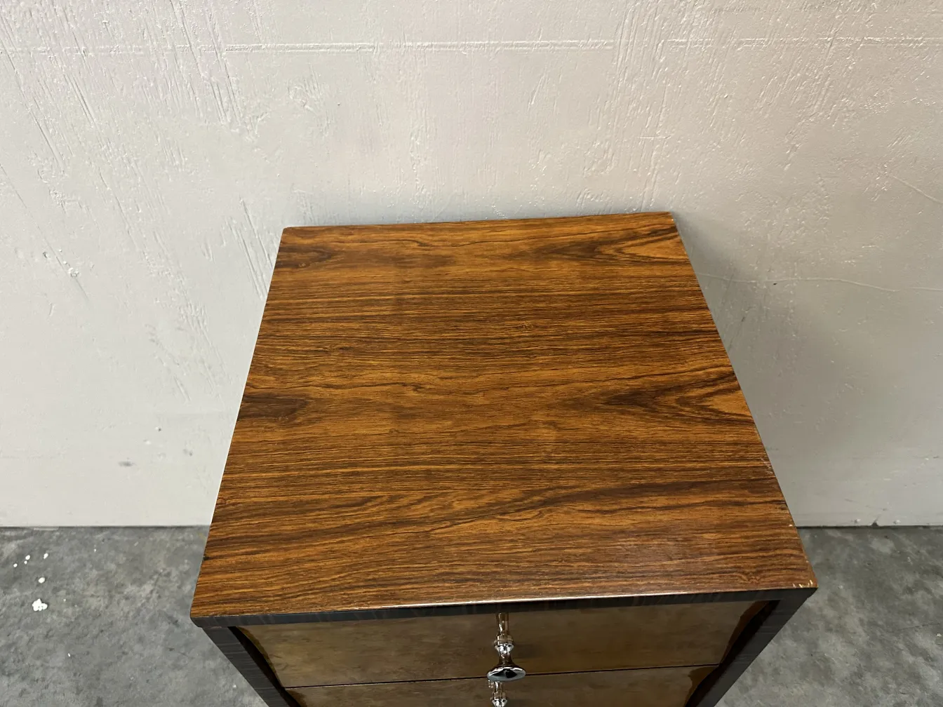 Vue du dessus d'une commode antique avec deux tiroirs dans un environnement minimaliste.