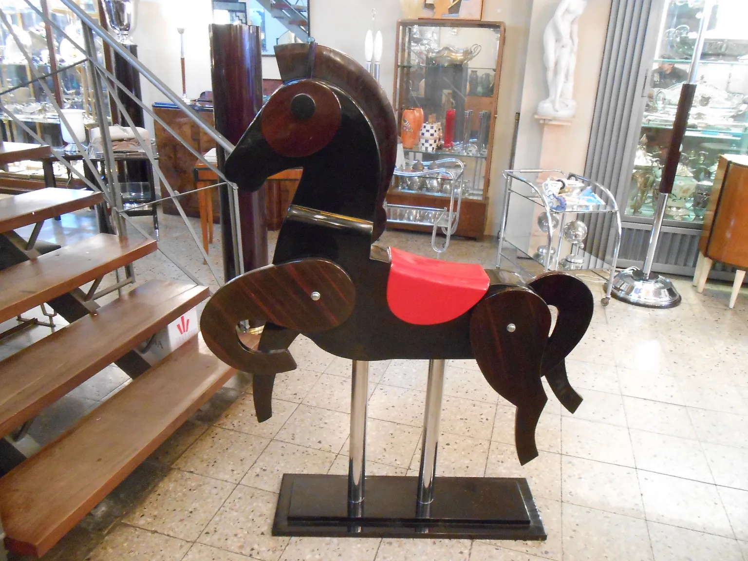 Antique horse decoration with red saddle and black base.