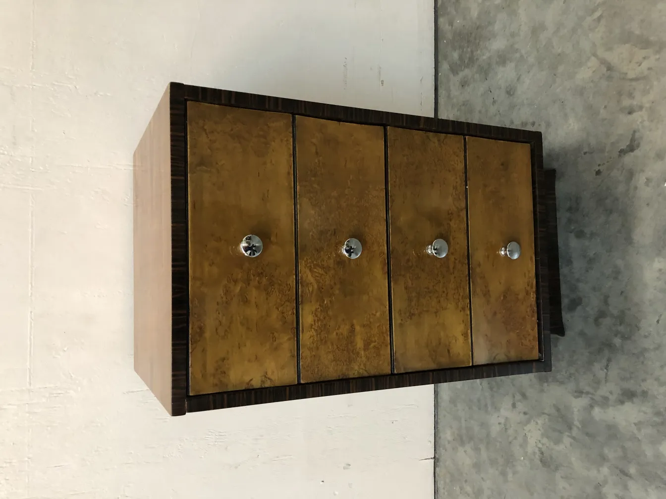 Antique cabinet with four decorative drawers, warm ambiance.