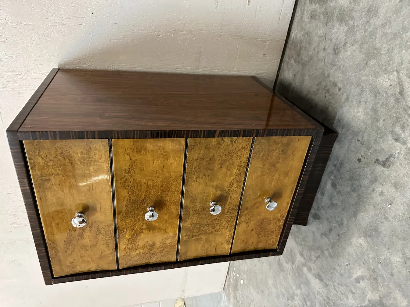 Comoda antigua con tiradores brillantes y cuatro puertas amarillas.