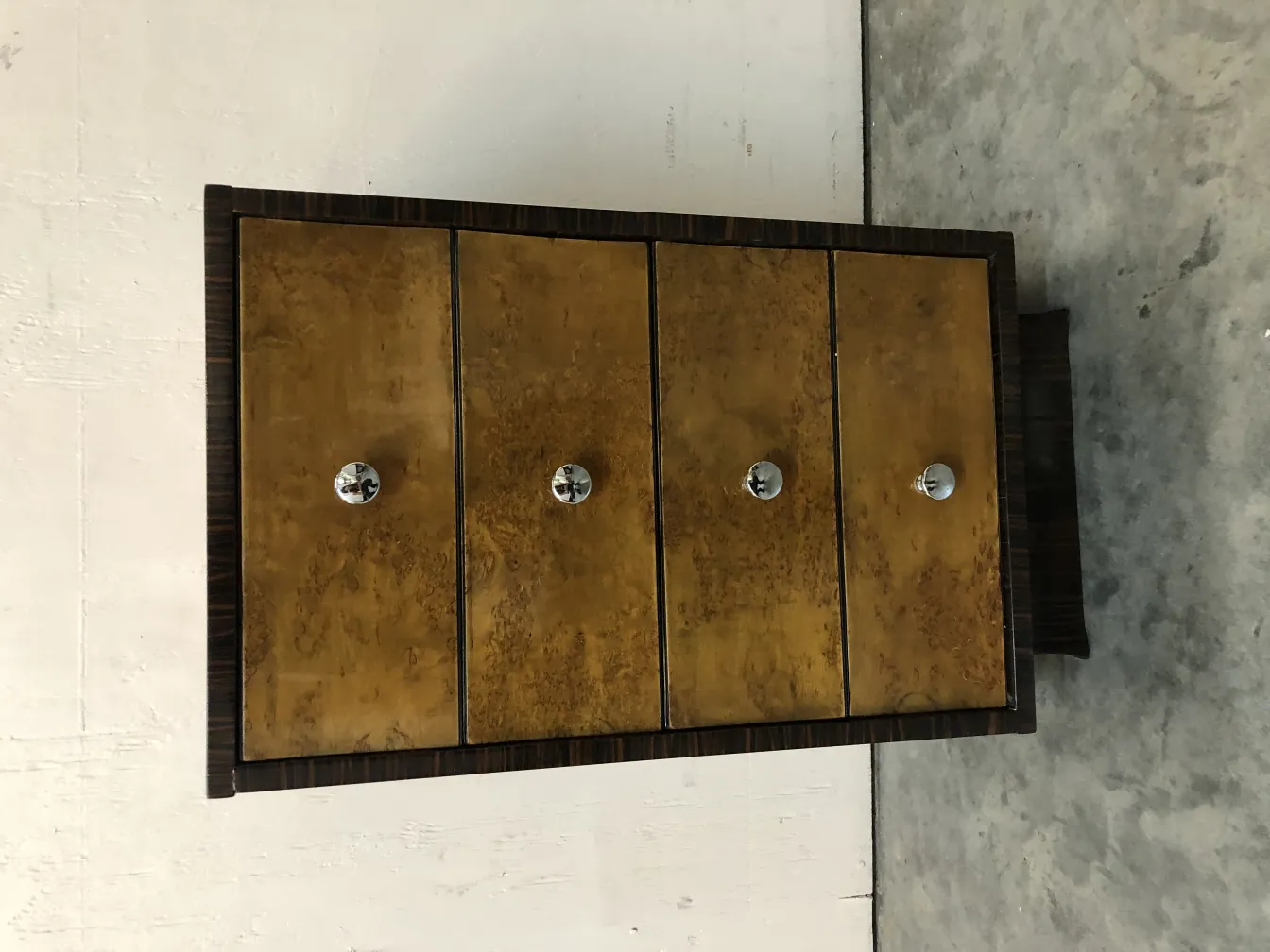 Cassetto antico con quattro cassetti e dettagli eleganti in un contesto semplice.