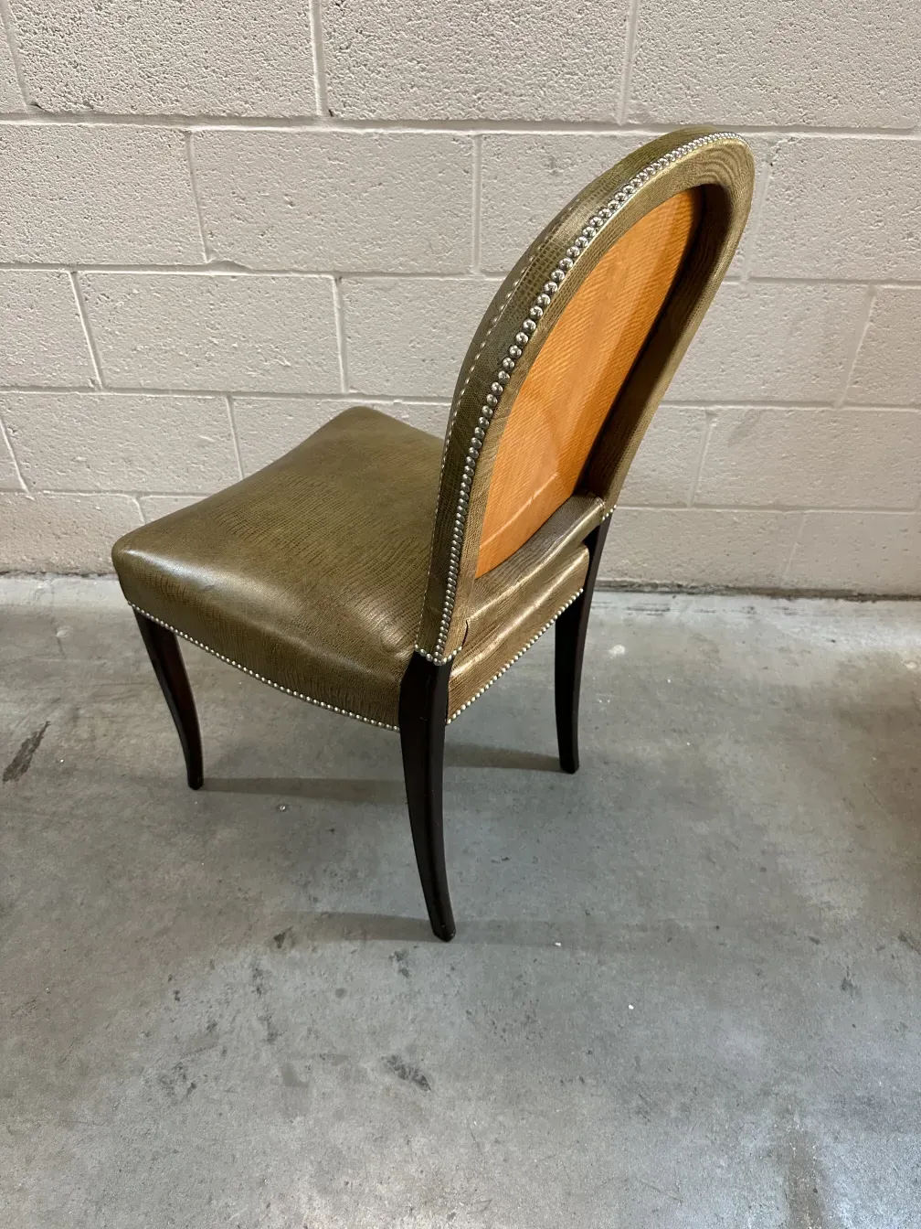 Side view of 12 antique chairs with elegant details, gray background.