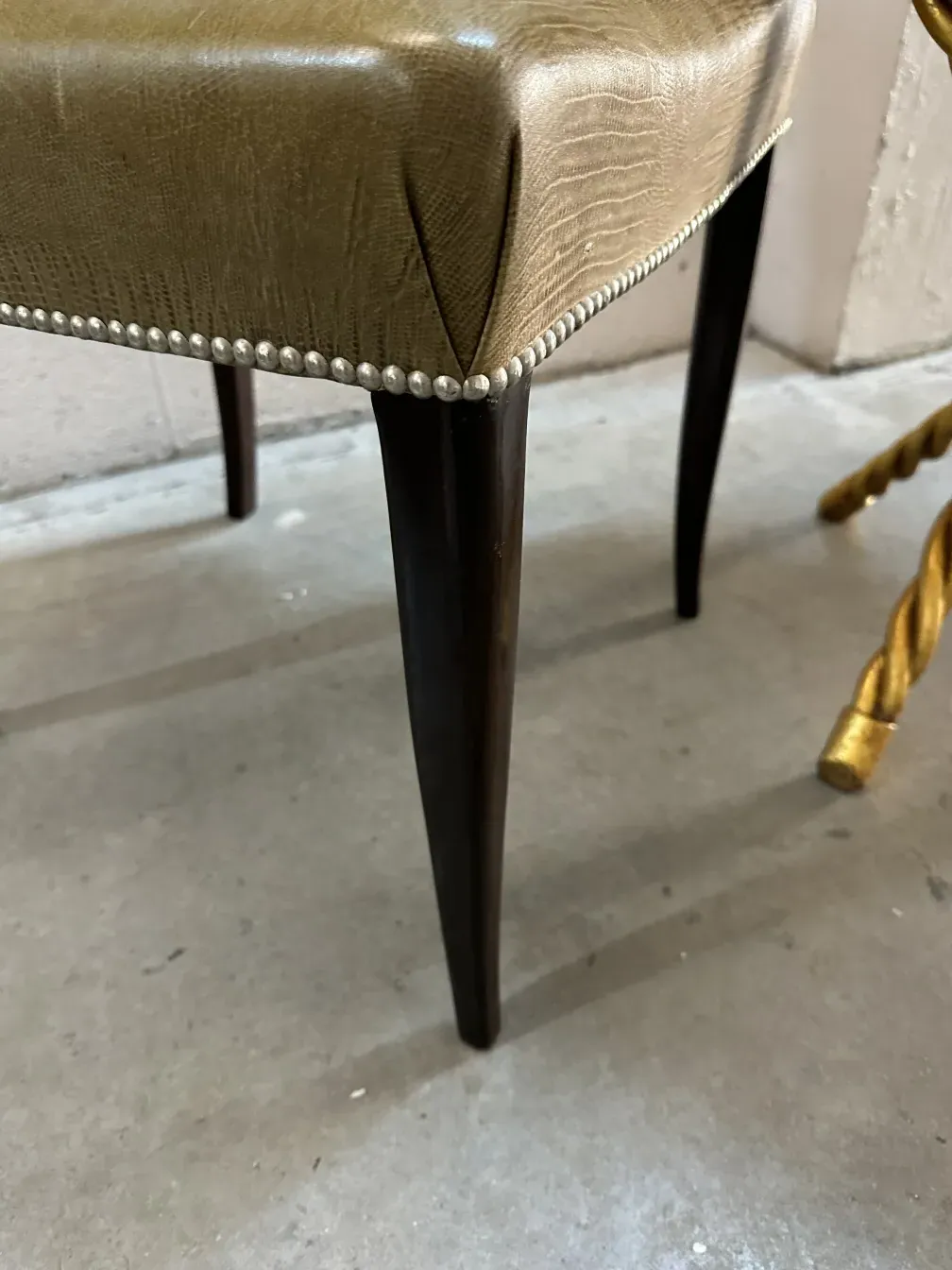 Vista lateral de sillas antiguas con diseño refinado y patas estilizadas en un entorno moderno.