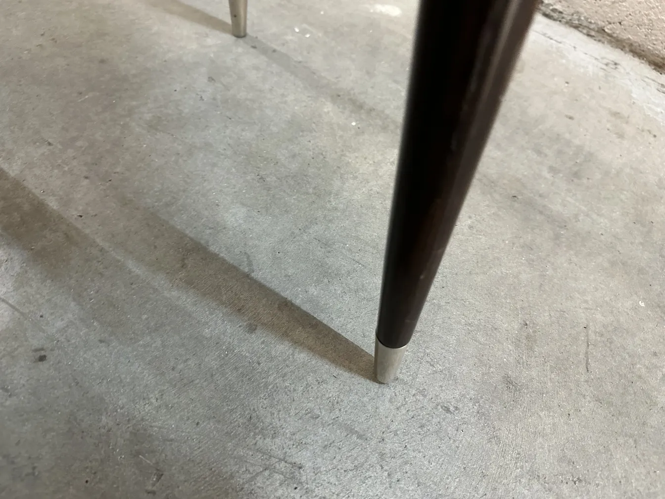 Vista detalhada das pernas de 12 cadeiras antigas carlo mollino, com sombras no chão.