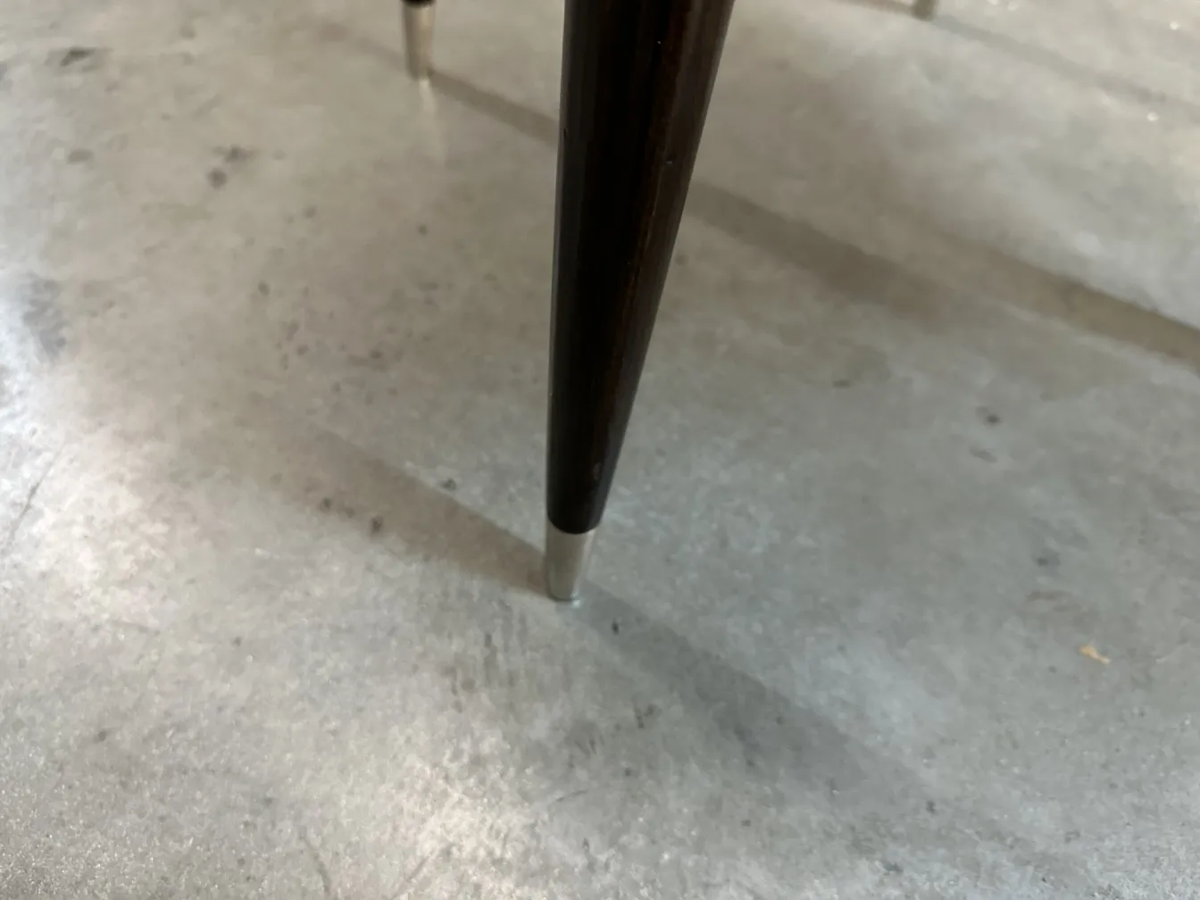 Primer plano de la pata de una silla antigua con un detalle elegante, perteneciente a carlo mollino.