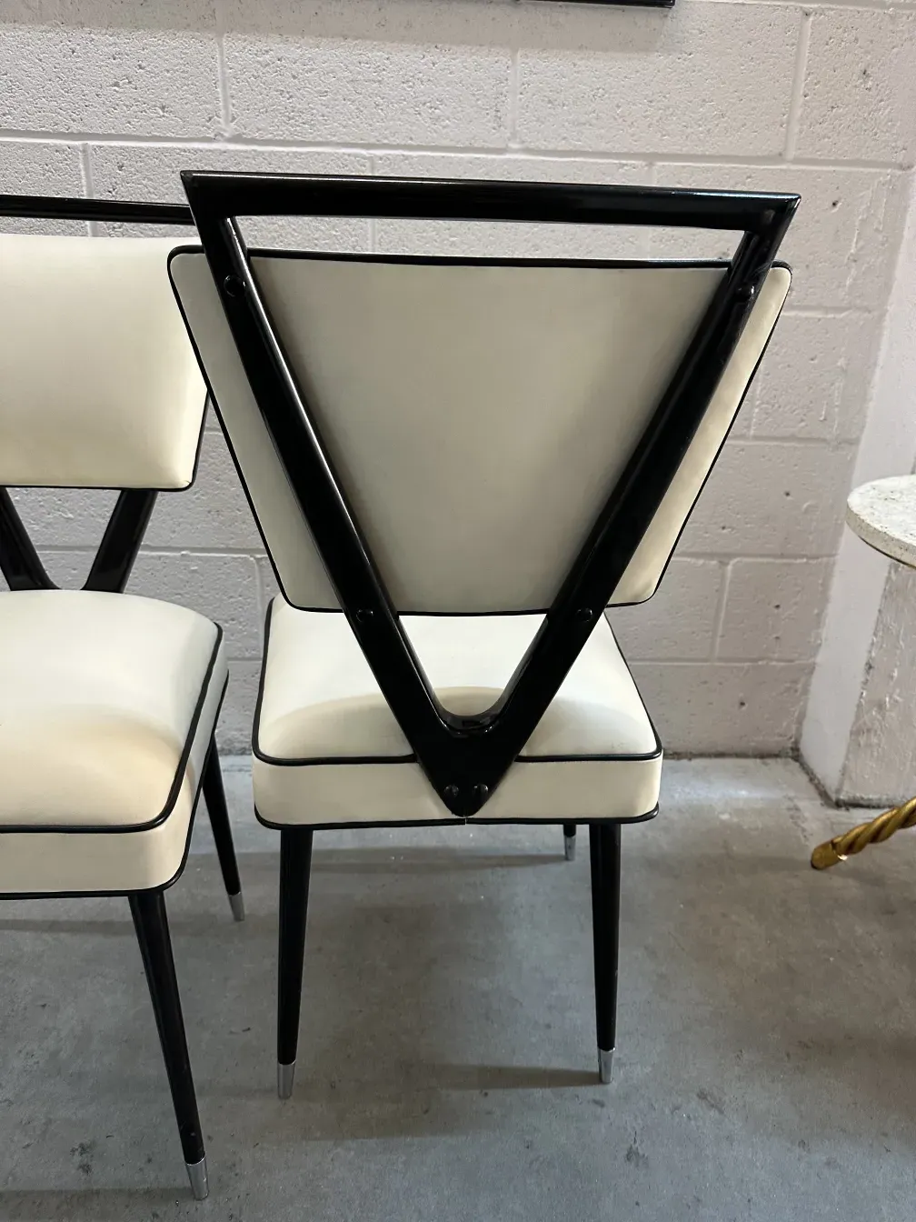 Dos sillas antiguas con acabado elegante, con detalles en color claro y oscuro, en un ambiente moderno.