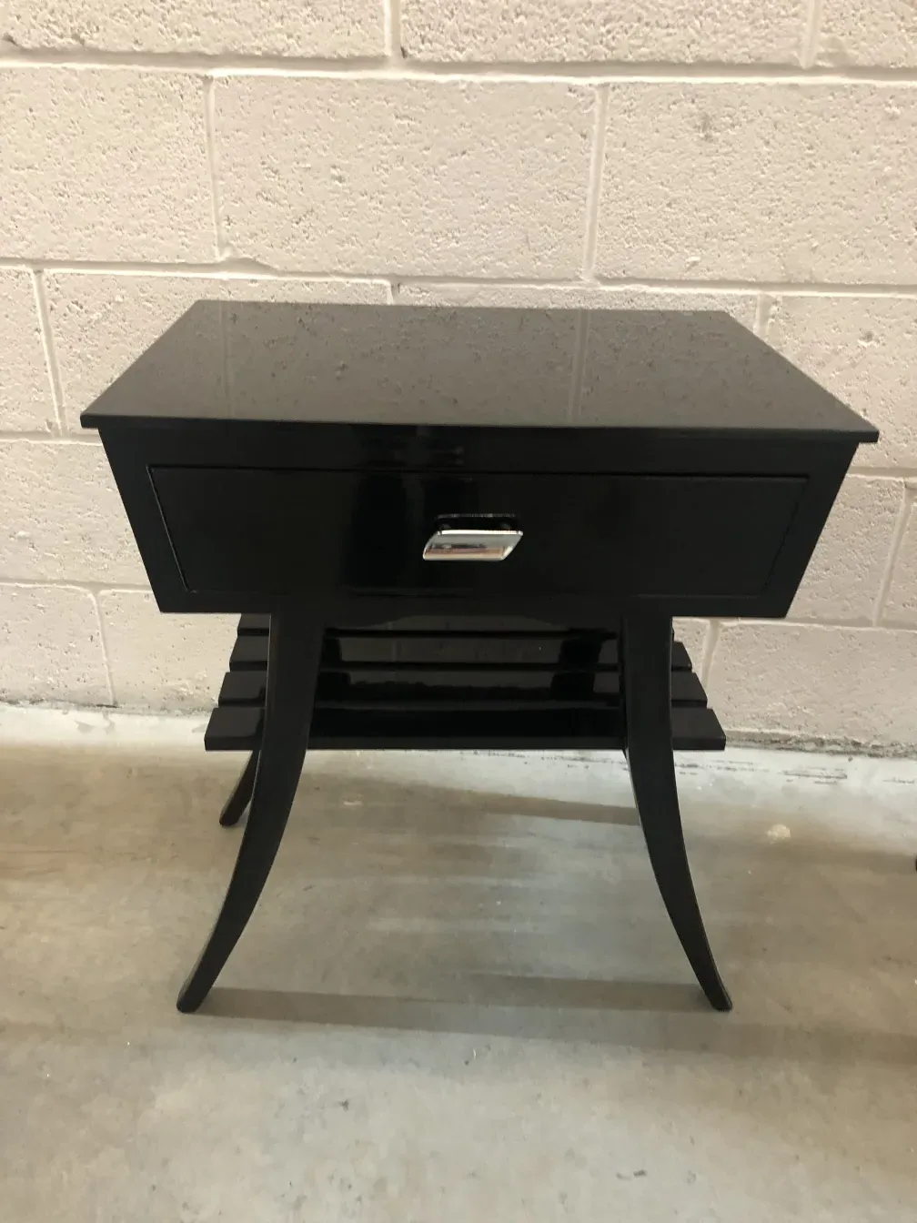 Mesa de luz antigua con cajón y patas curvadas, en ambiente minimalista.