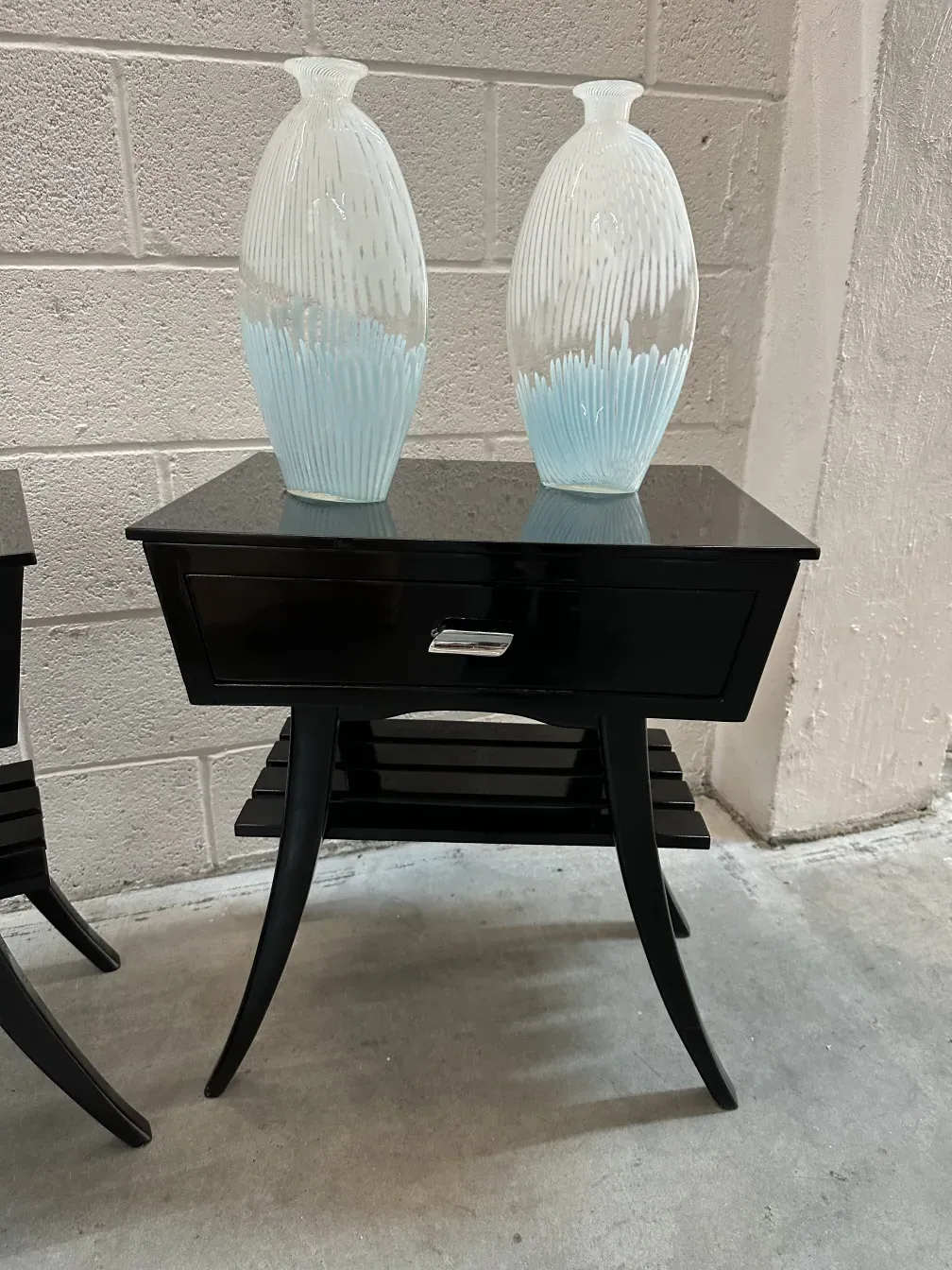 Mesa de luz antiga preta com dois vasos decorativos em cima.