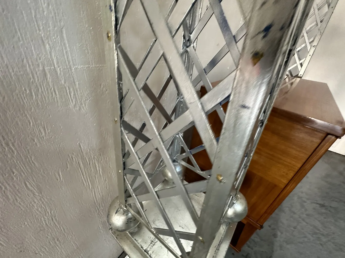 Obelisco antiguo con diseño decorativo en color brillante, ubicado junto a un mueble.