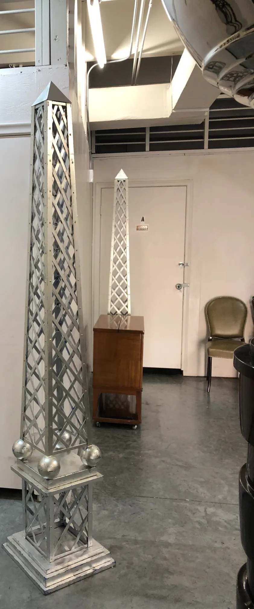 Obelisco antigo com base decorativa e esferas metálicas, ambiente interno