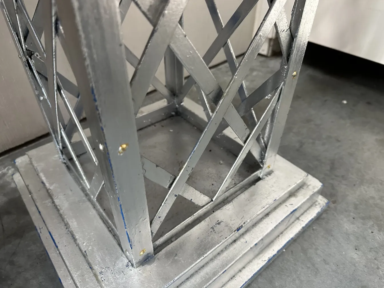 Antiker dekorativer Obelisk mit verzierten Fuß und kompliziertem Design vor einem subtilen Hintergrund