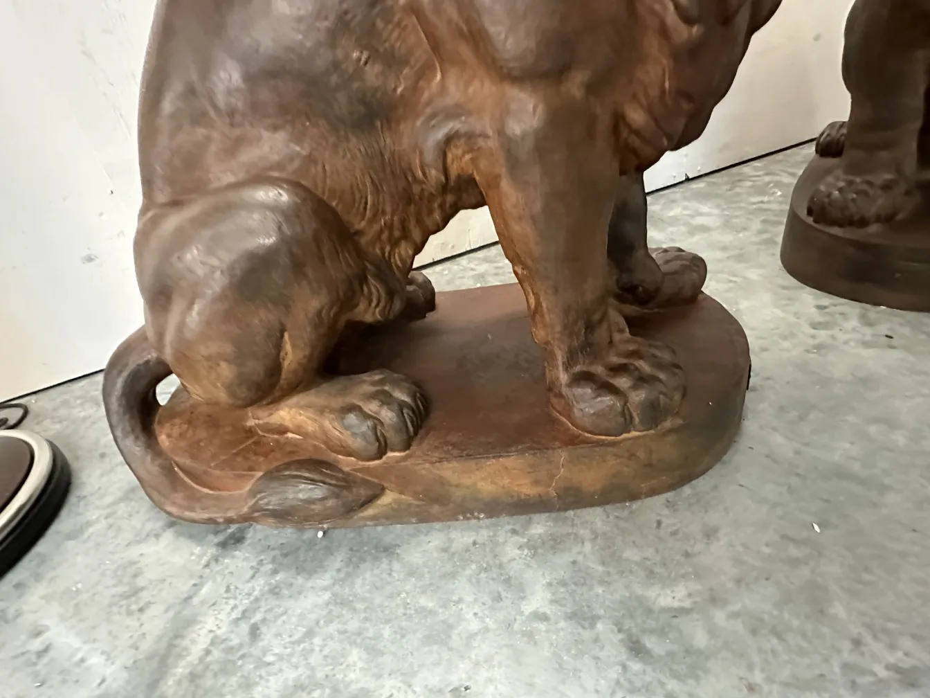 Two antique lions with detailed base, set in a neutral background.
