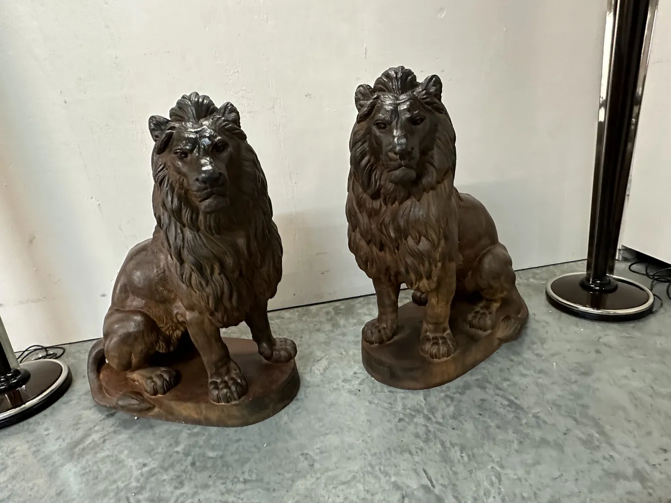 deux lions anciens avec des détails soignés et des expressions fortes, assis sur des bases