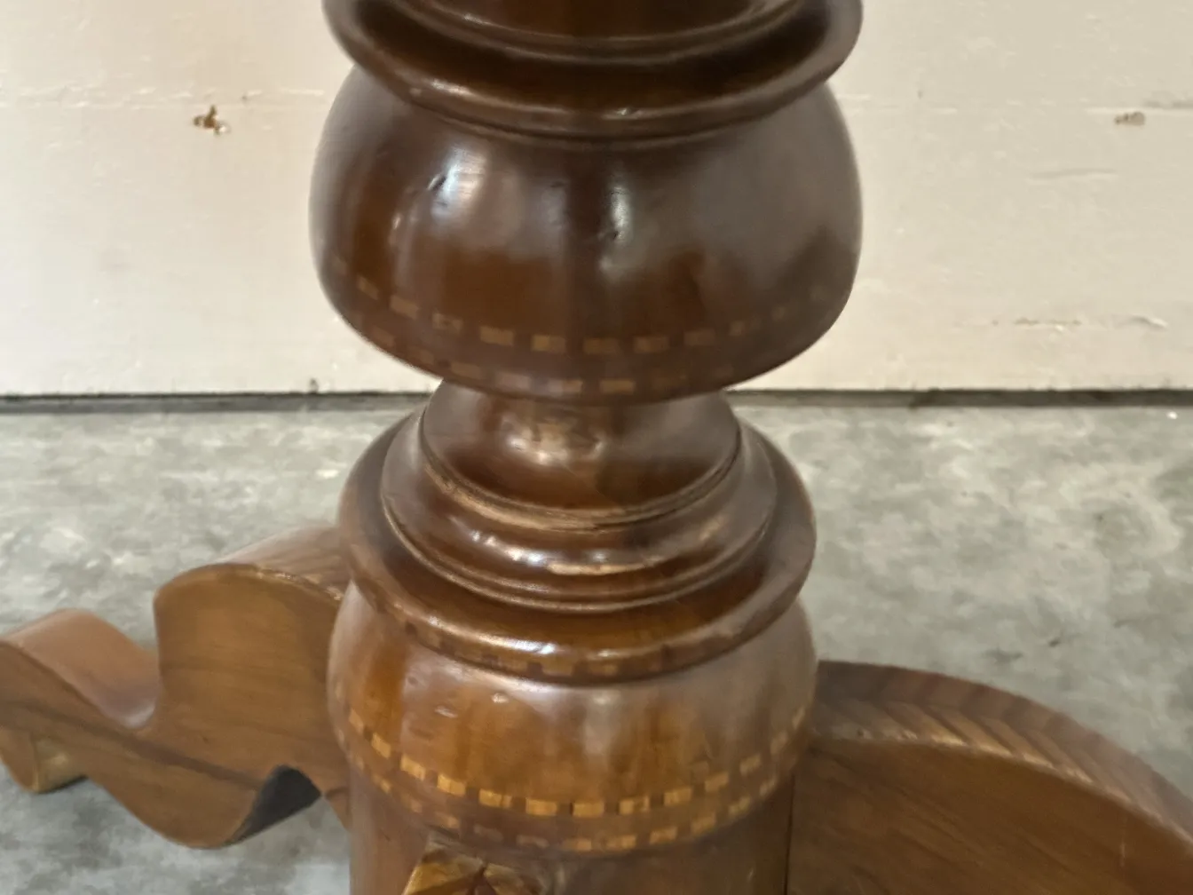 detalle de una mesa antigua con base tallada y decorativa